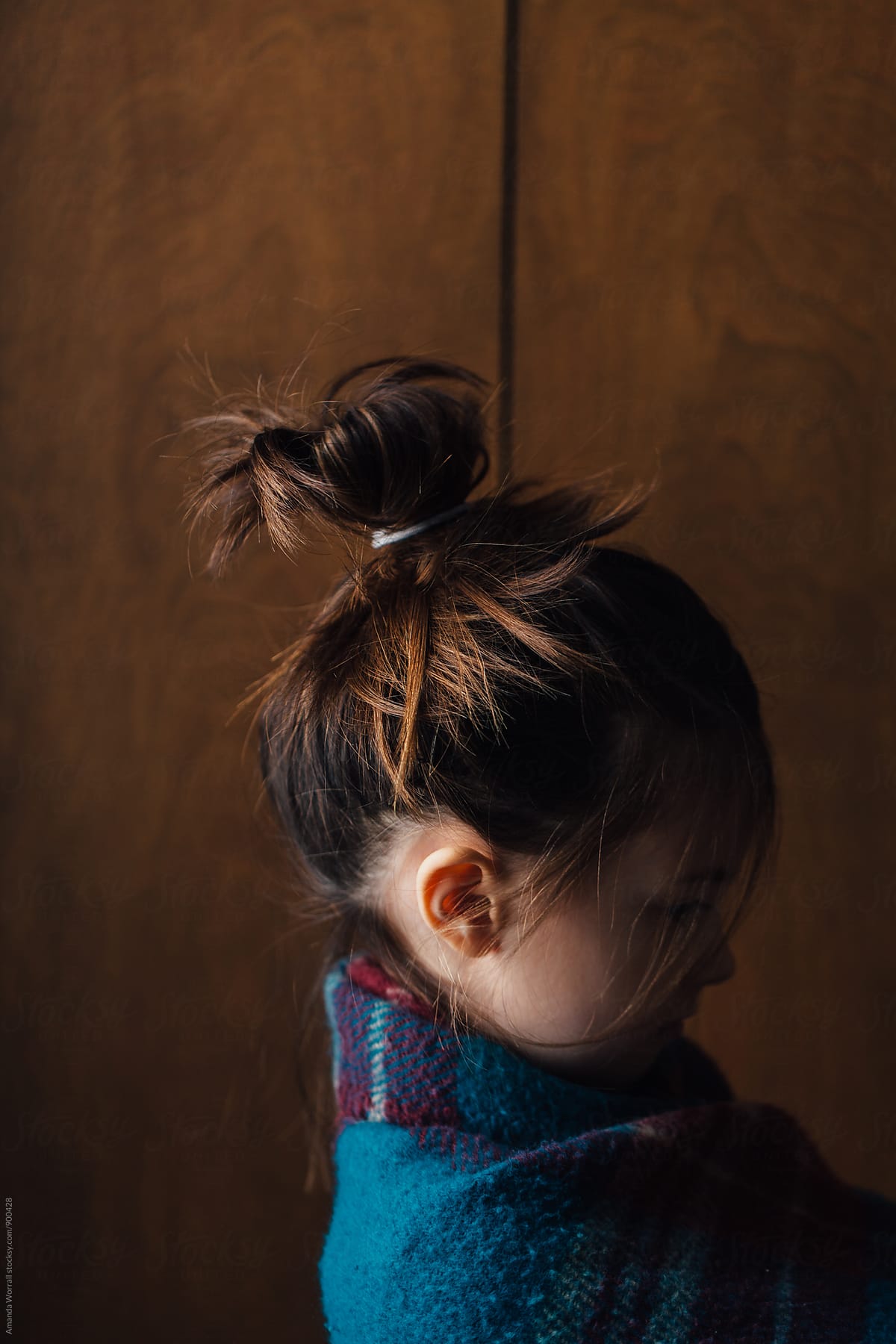Profile portrait of young girl wrapped in a blanket, hair up in a messy bun