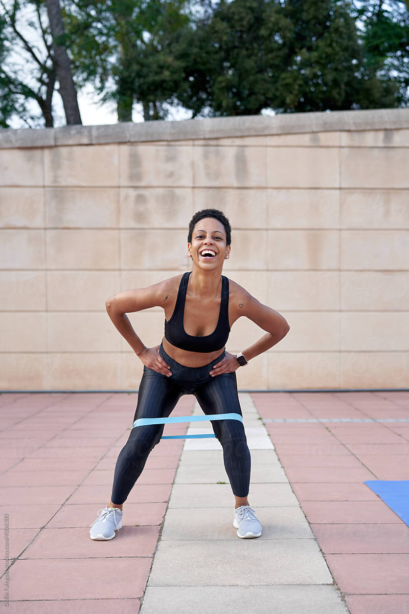 Happy black sportswoman exercising with resistance band