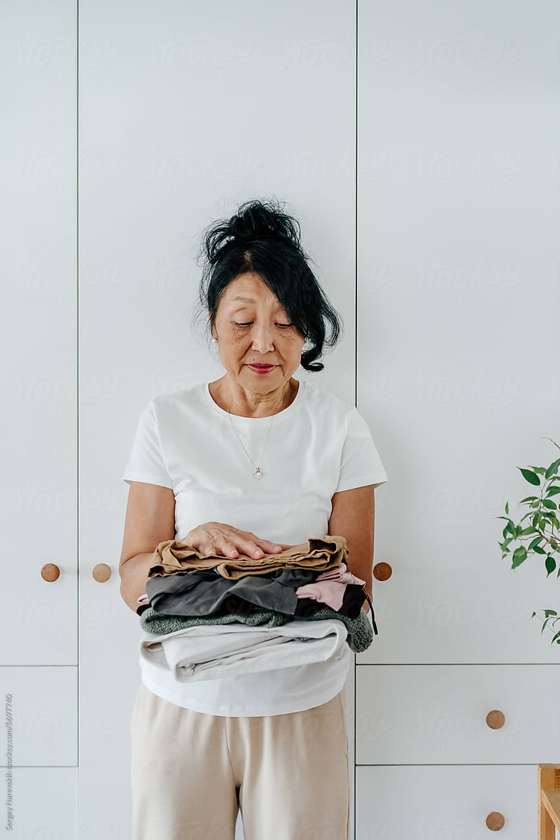 Senior asian woman standing near closet, reasonable consumption