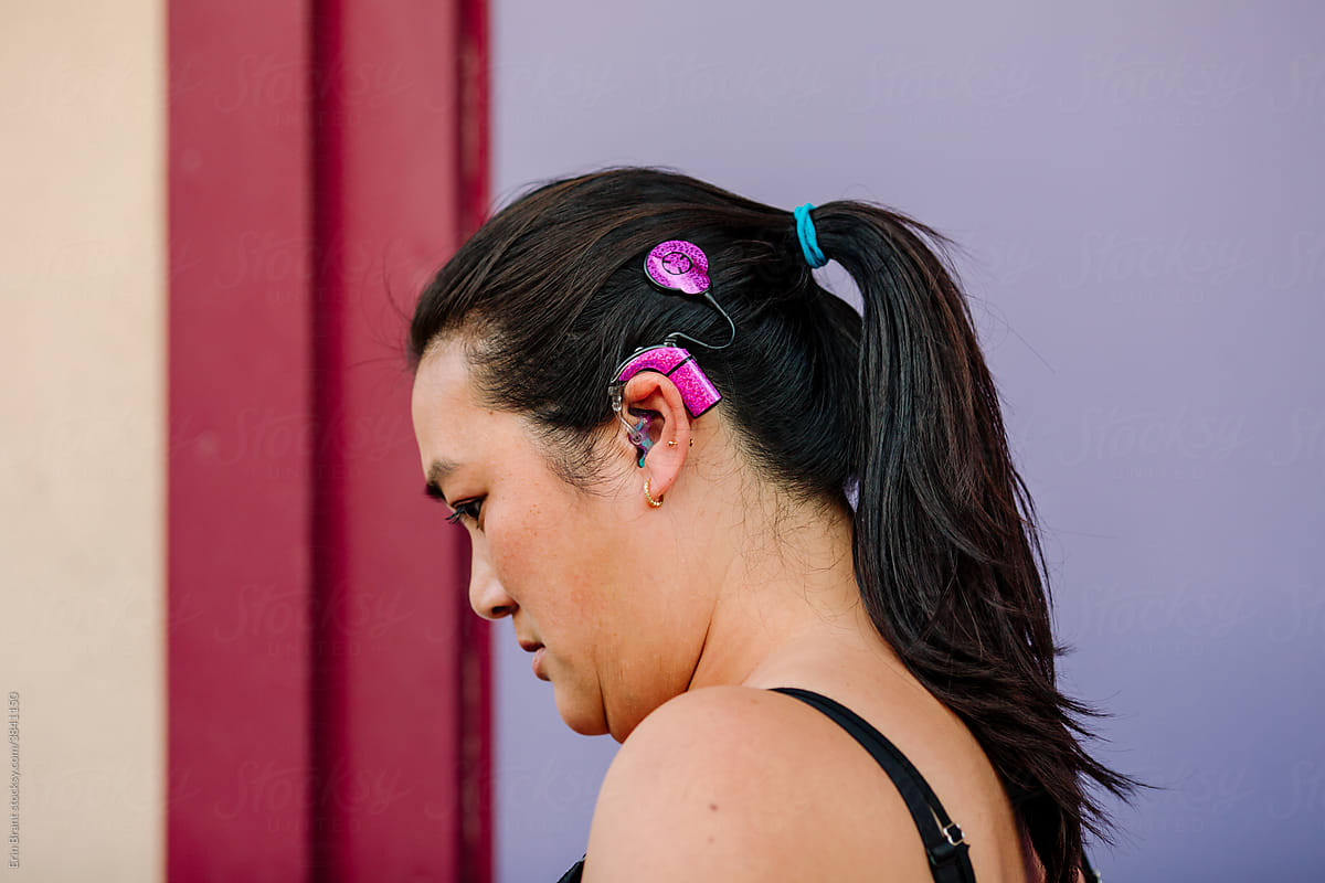 Asian woman with pink cochlear implant skins