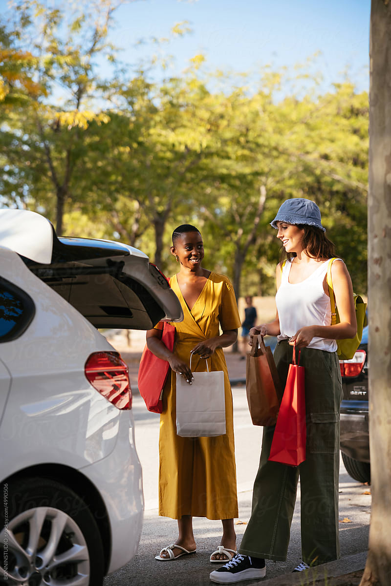 Diverse women standing near car after shopping