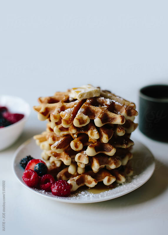 Waffles on a plate topped with berries and butter