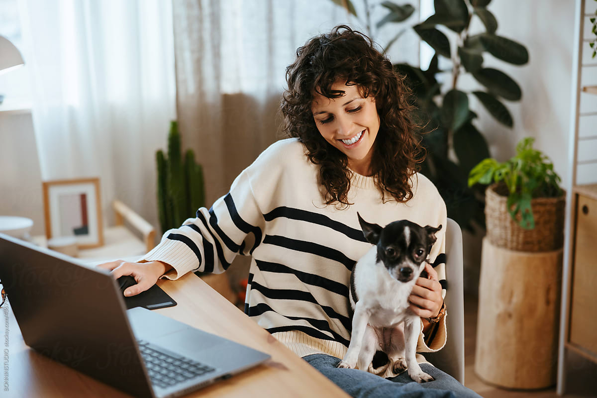 Cheerful female freelancer petting dog