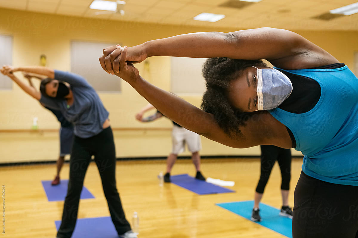Gym: Group Wearing Face Masks Participates In Stretch Class