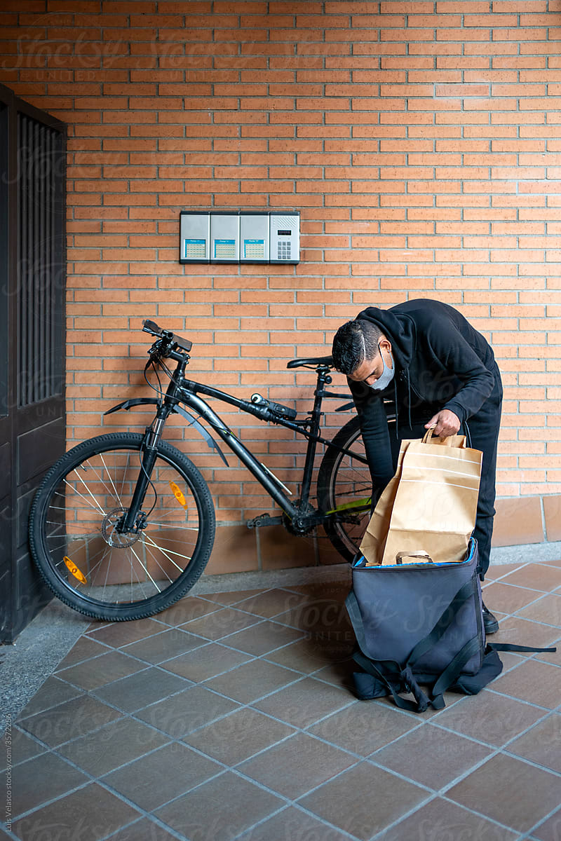 Courier With Bike Delivering Food To A House.