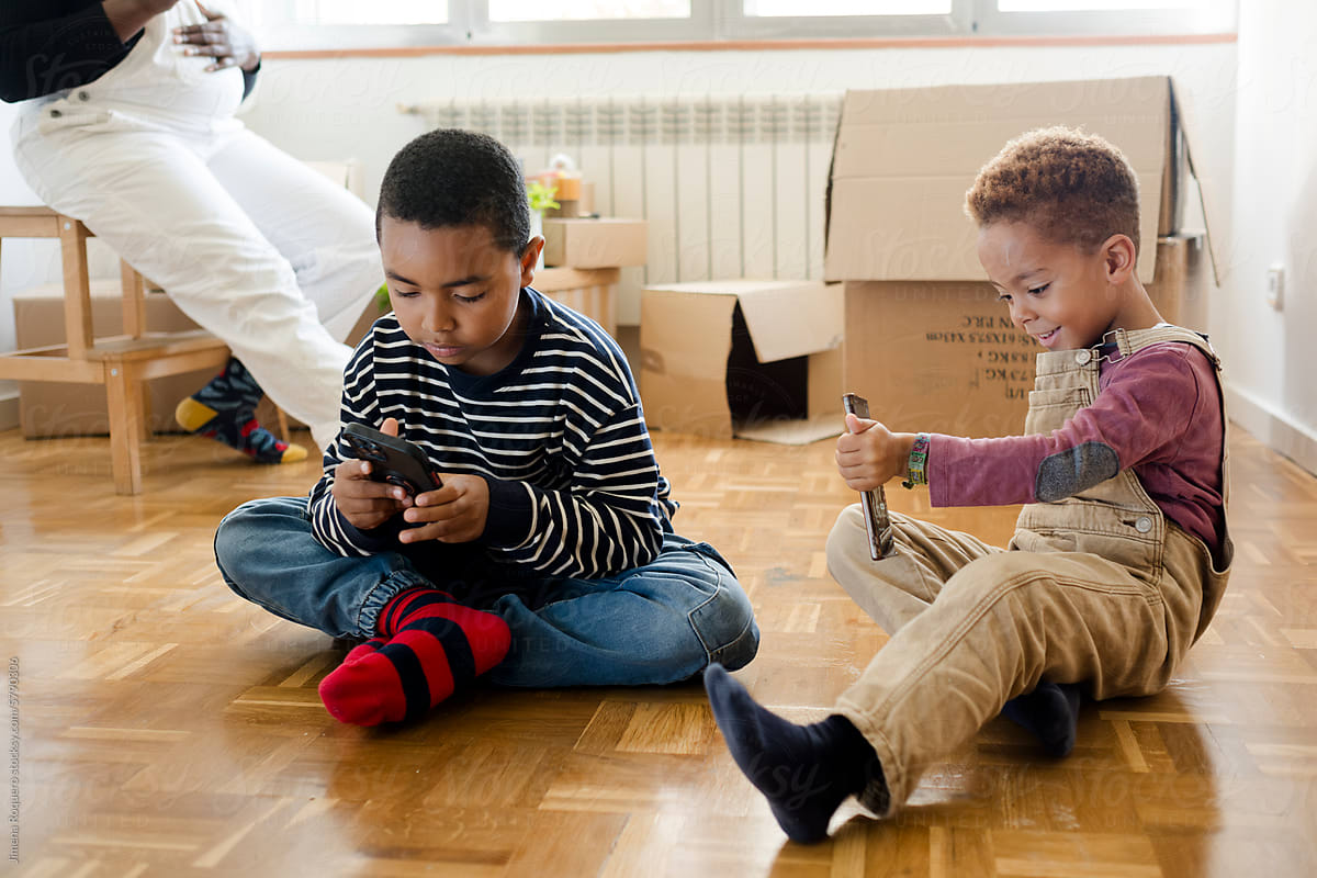 Kids playing videogames in smartphone in new empty home