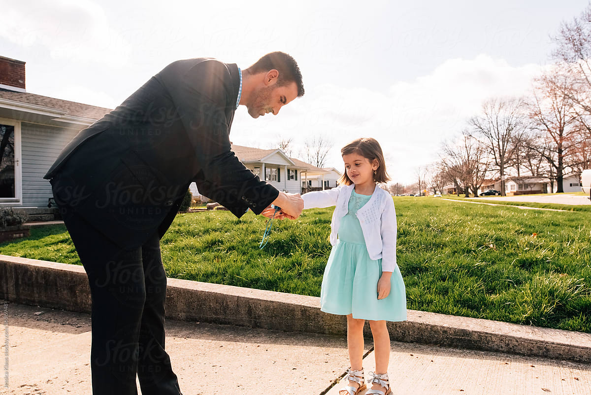 Father putting flower corsage on daughter\'s wrist.