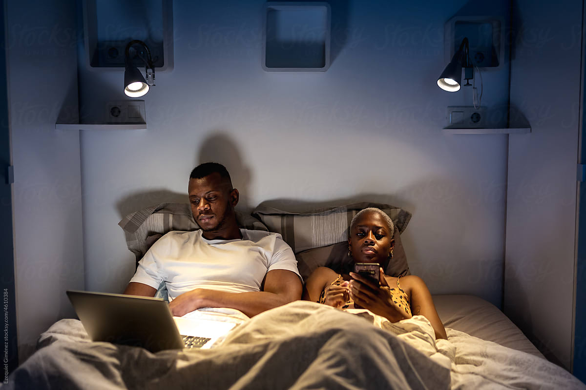 Black couple using devices on bed
