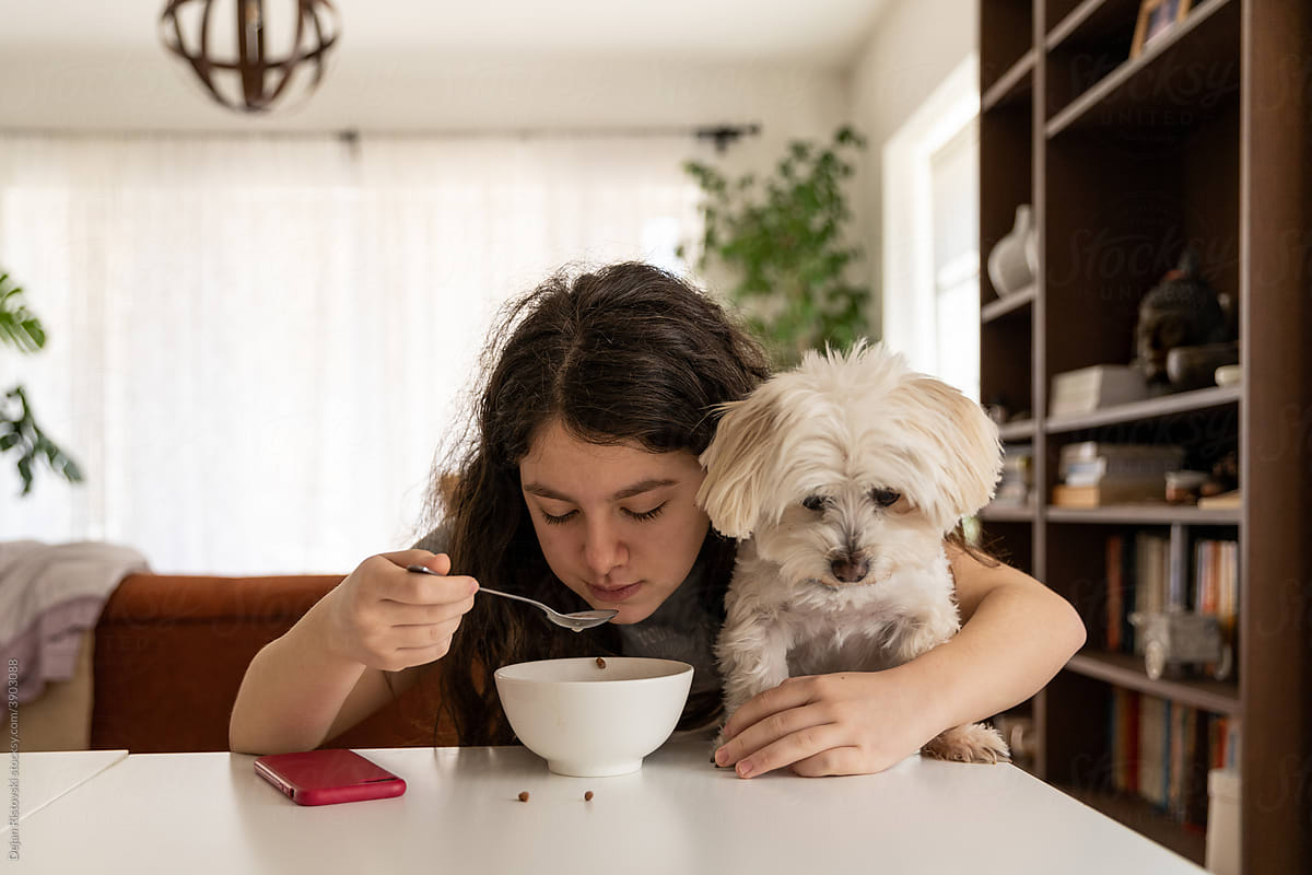 Girl and her dog eating breakfast