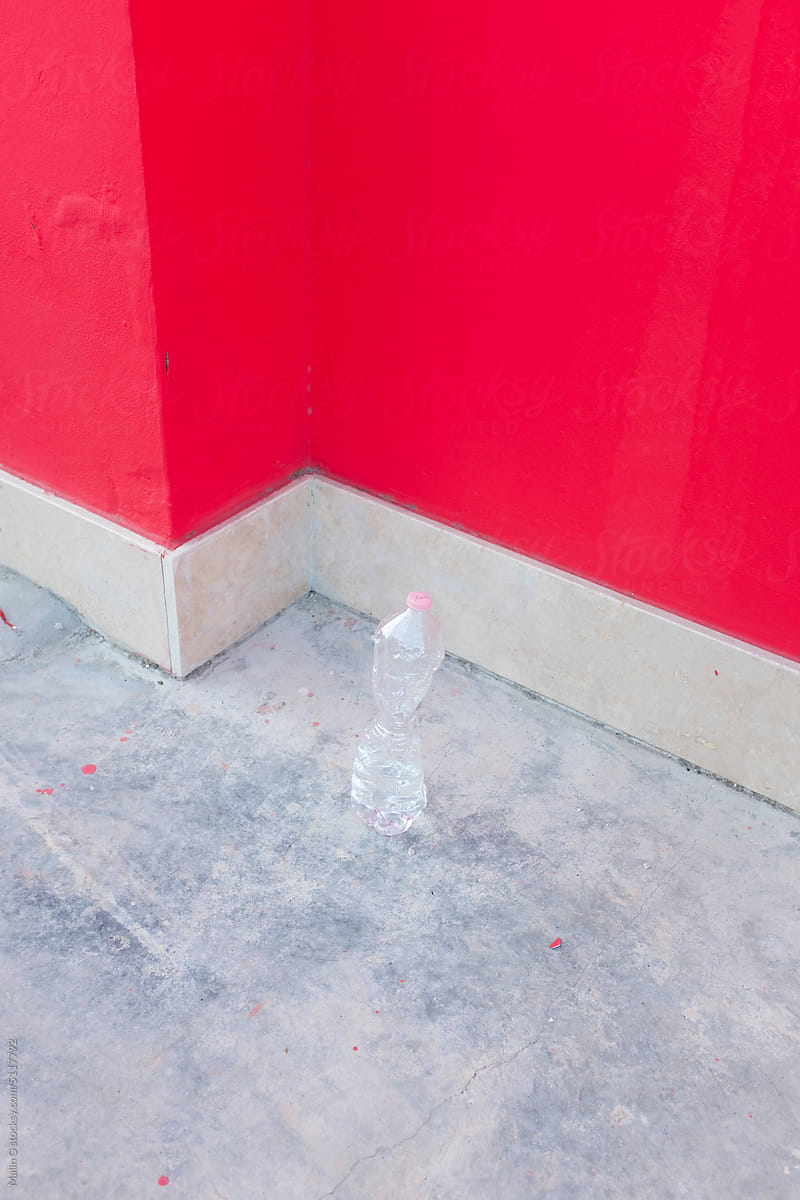 A water bottle in a front of bright pink wall