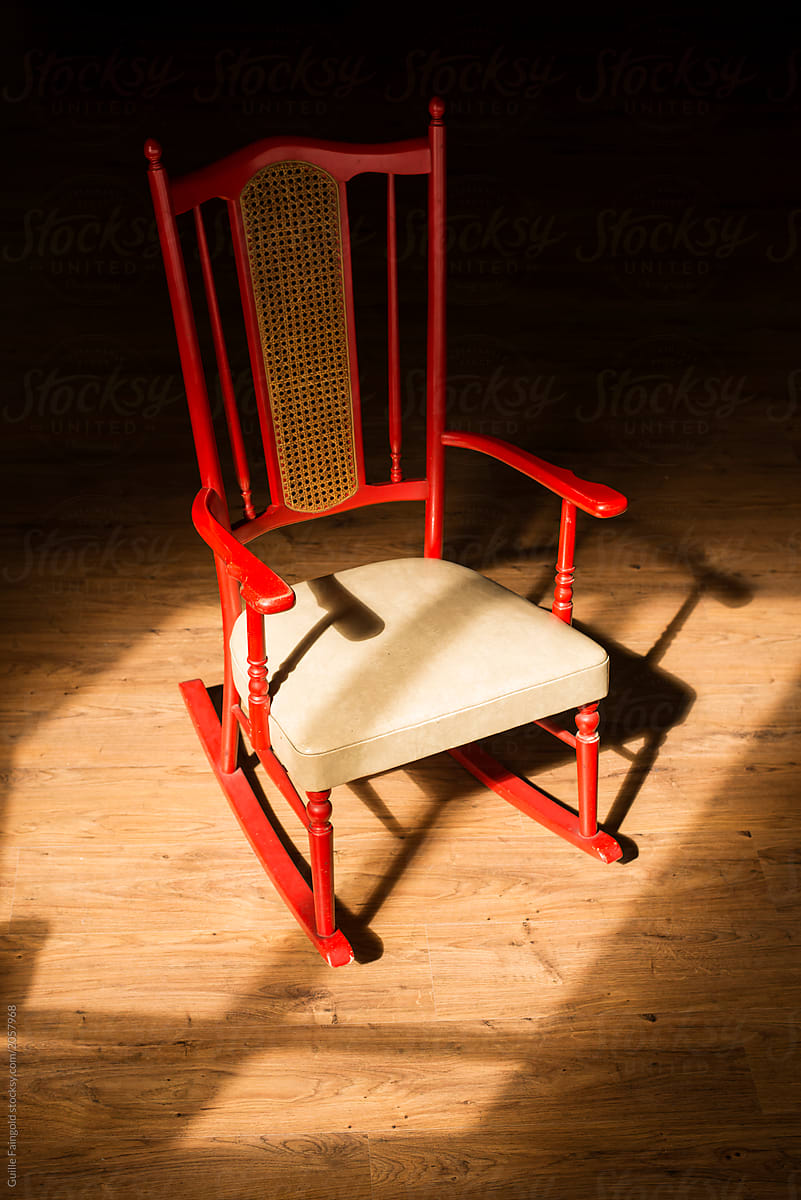 A lonely red chair in sunlight.