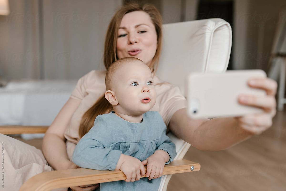 Mom with little daughter taking selfie photo on smartphone.