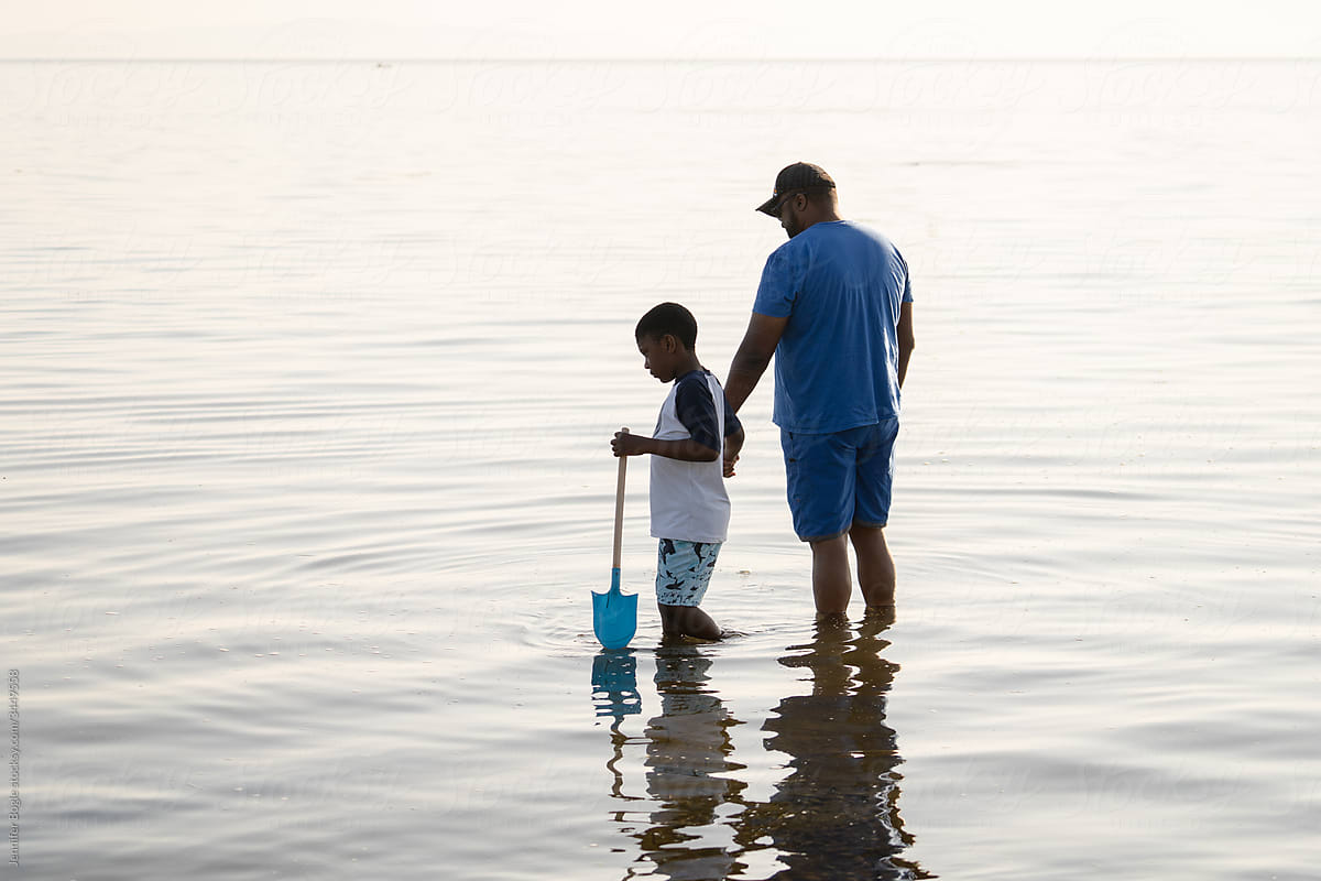 Black father and son wading into ocean