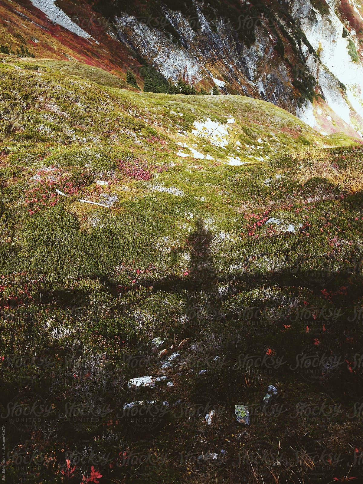 Shadow of hiker in mountains and alpine meadow, autumn