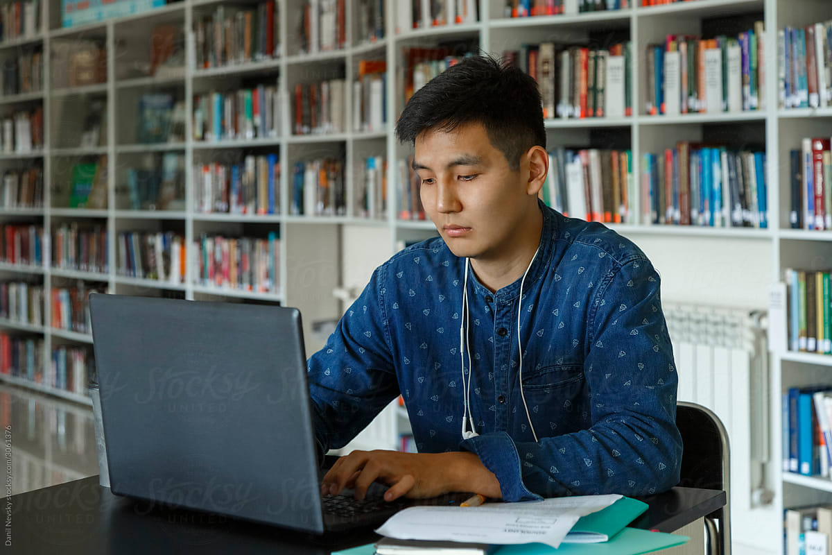 Asian student using laptop in library