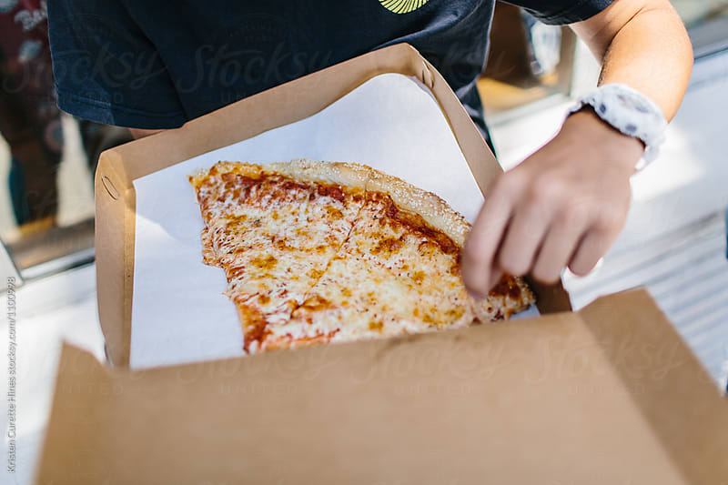 Close up of a man grabbing a slice of pizza