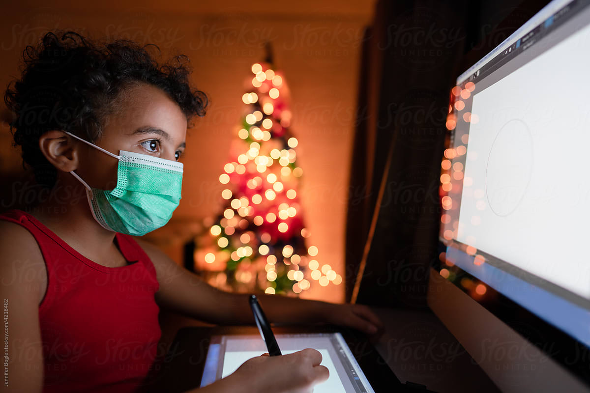 Masked girl draws on computer tablet at Christmas