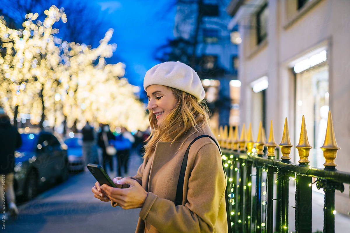 Smiling woman browsing smartphone on city street