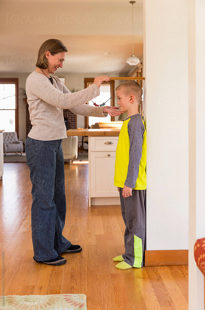 Family lifestyle measuring child against wall  at home