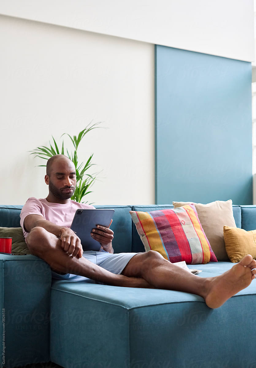 Relaxed Afro American man watching movie at tablet.