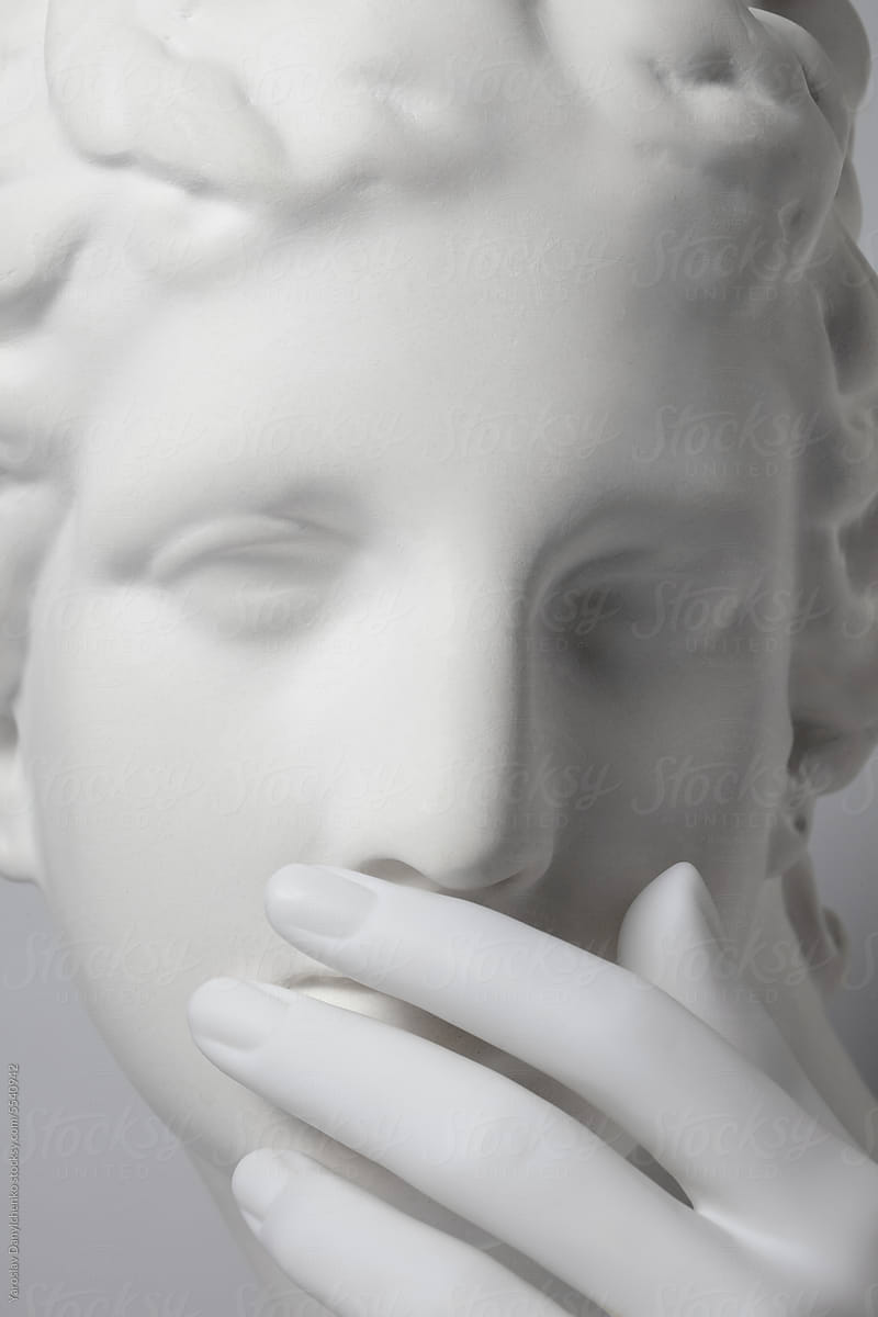 Marble statue covers mouth with her hand.