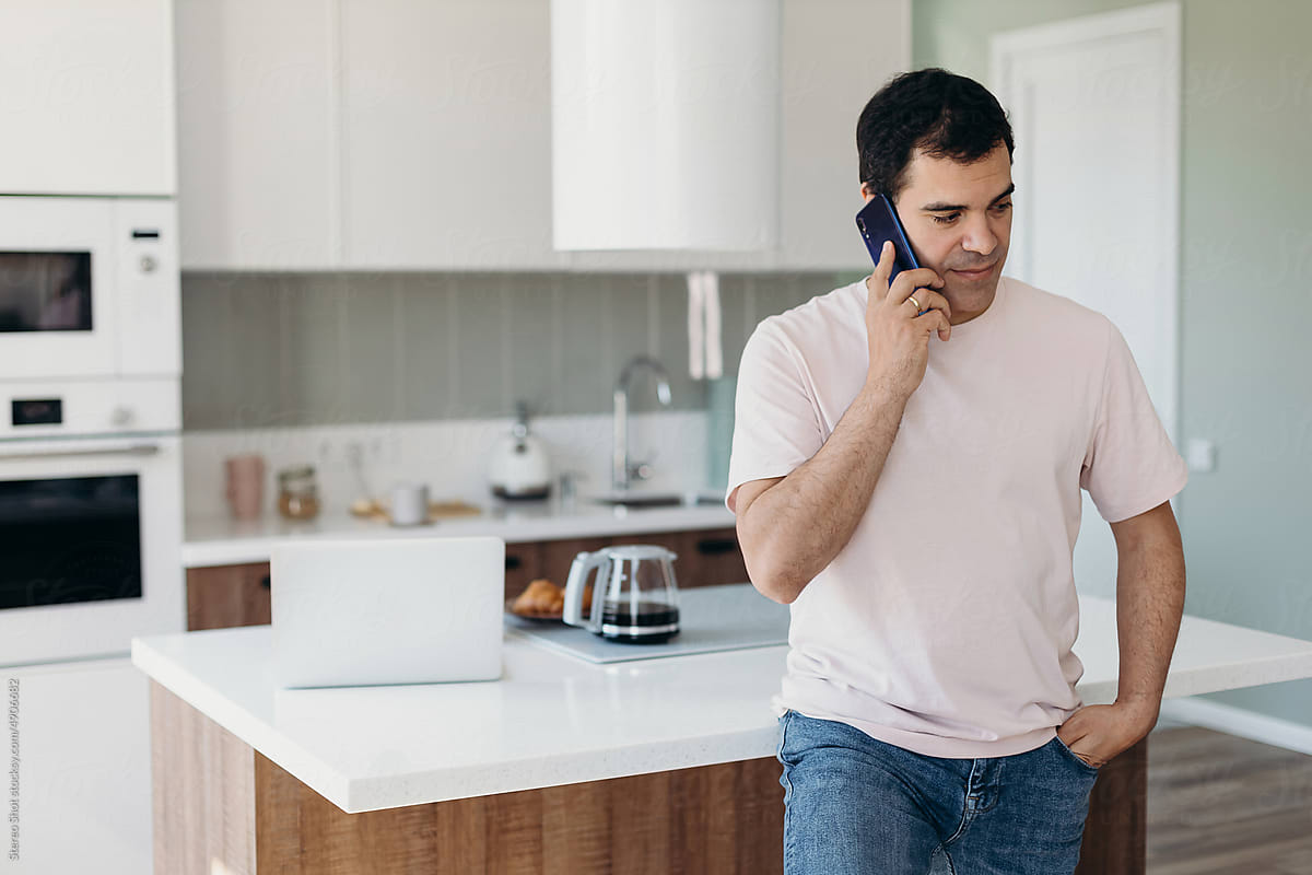 Middle aged man talking on cellphone near kitchen table