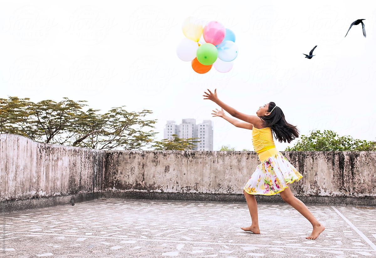 A Girl is playing with colorful balloons on the roof