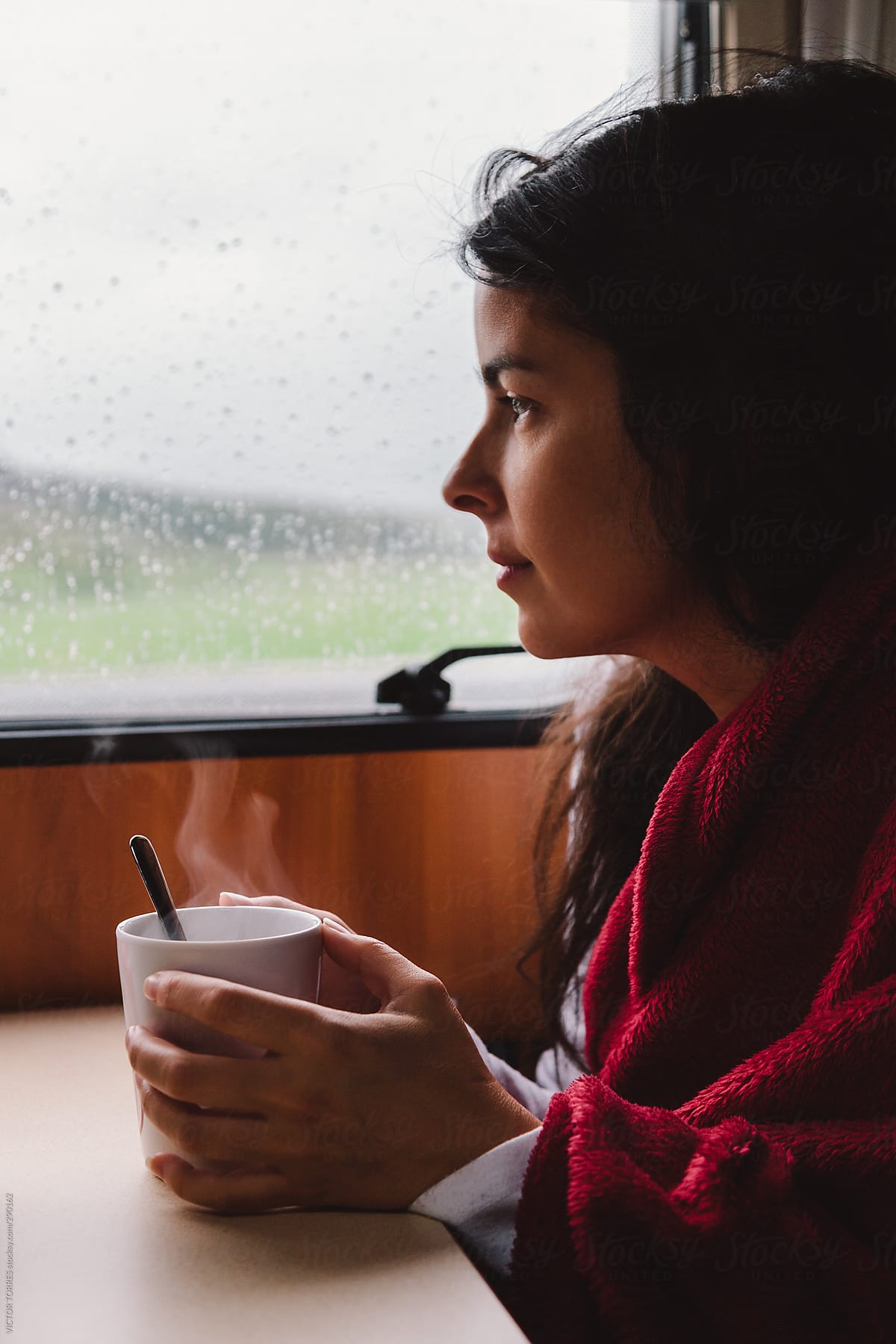 Young Woman Having a Warm Tea with a Red Blanket inside a Motorhome