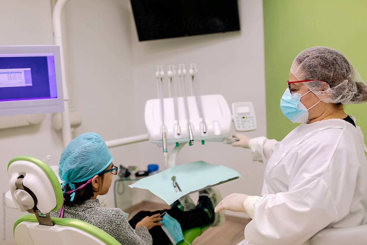 Female dentist showing tools to patient