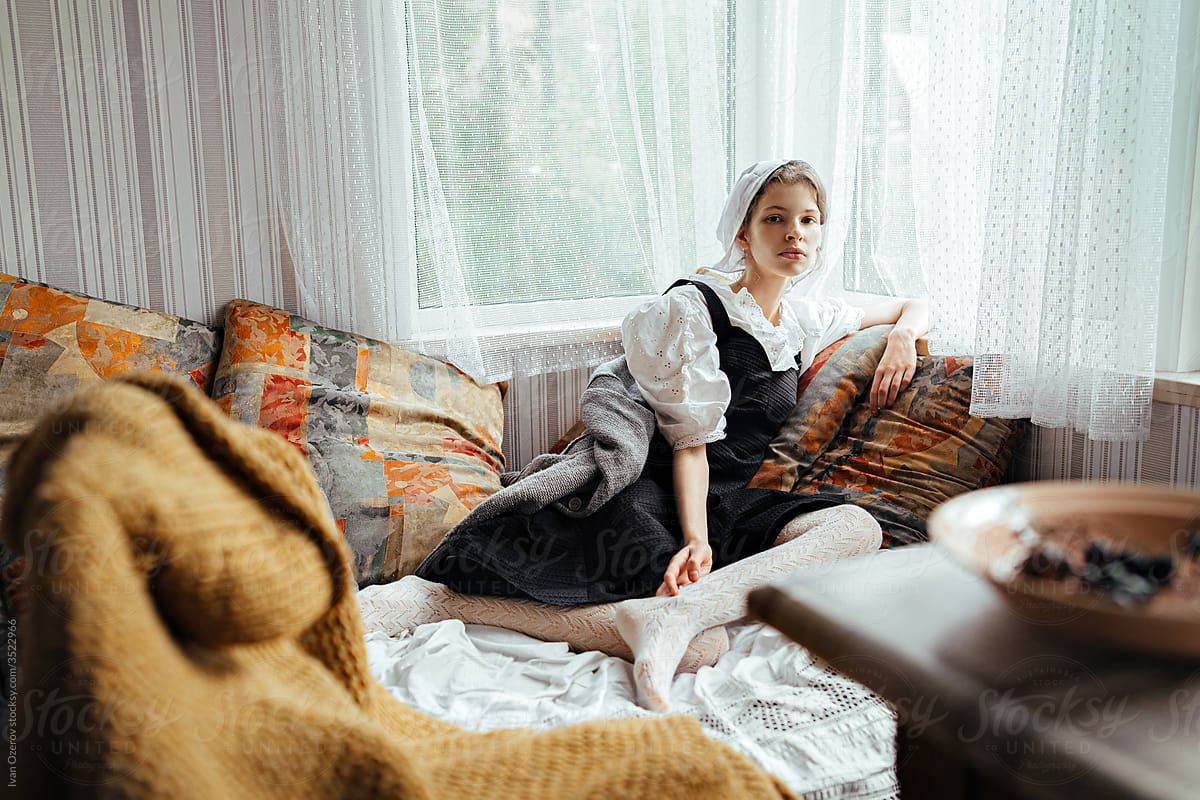 young girl in retro clothes sits on the couch