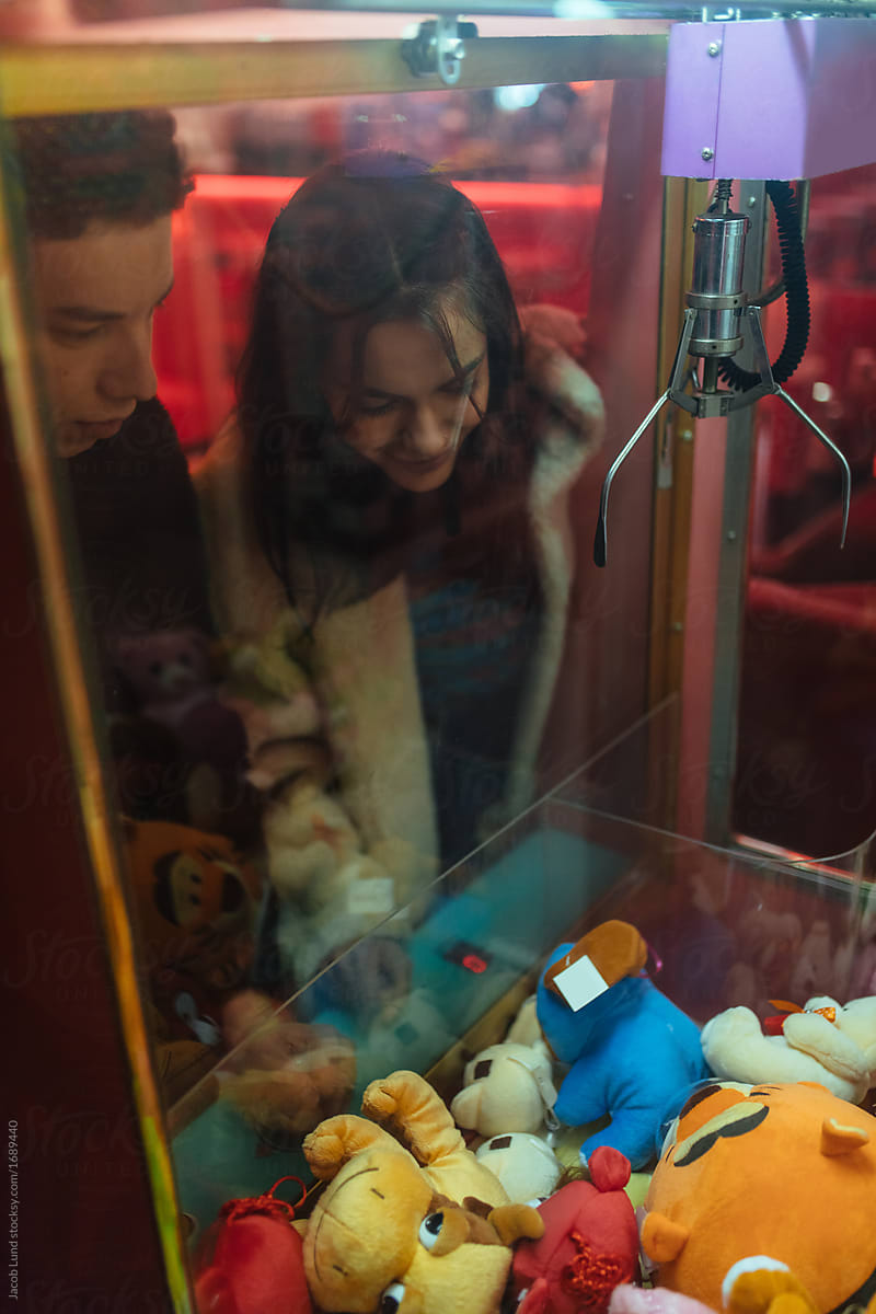 Couple playing claw game machine at arcade center