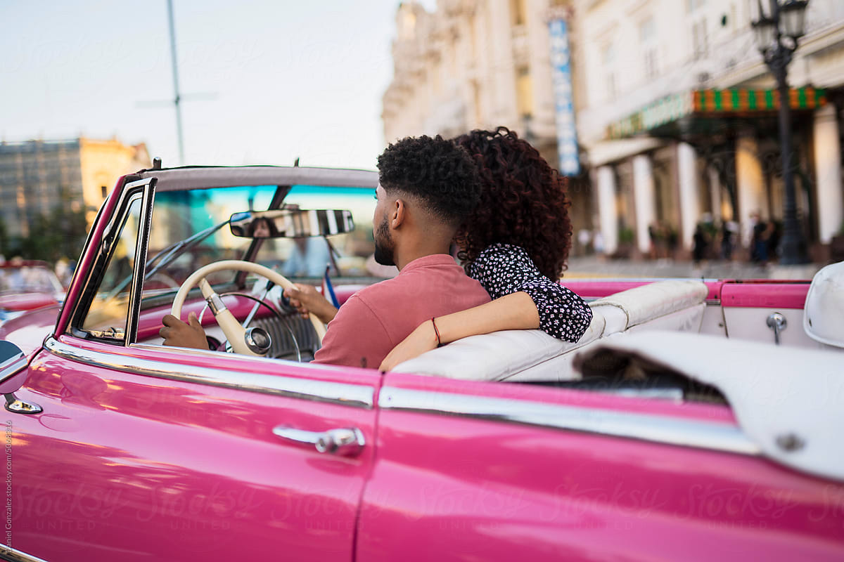 Cuban couple driving retro car in city