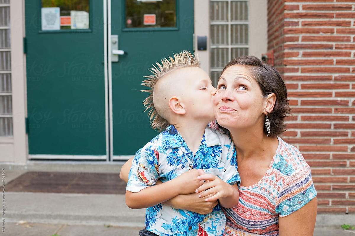 Five year old boy with mohawk kissing his mom on the first day of school