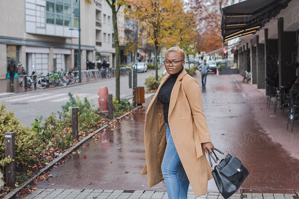 elegant black woman with short hair wearing coat in the city