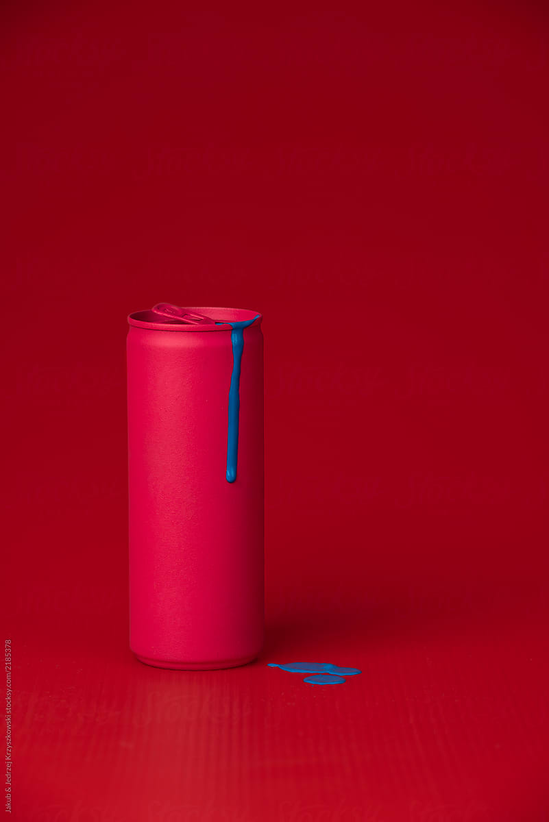 Pink can with blue paint dripping on red background