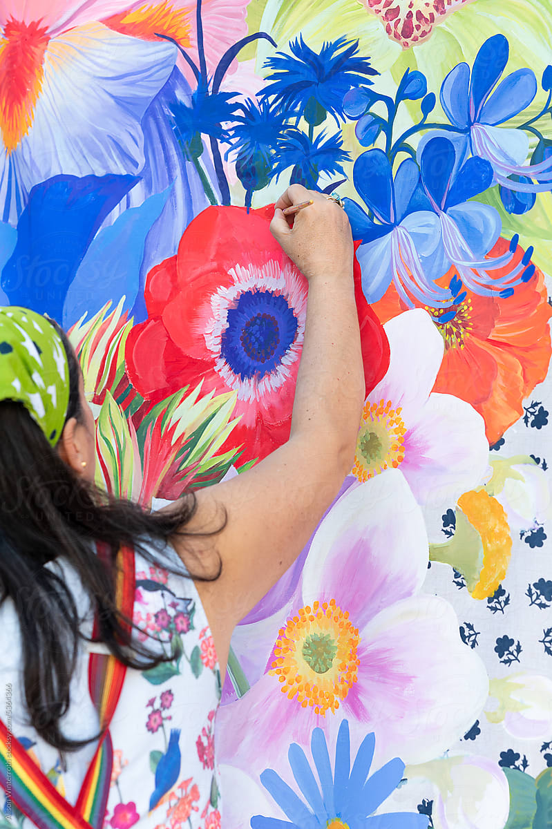 Up close of a woman painting a floral mural