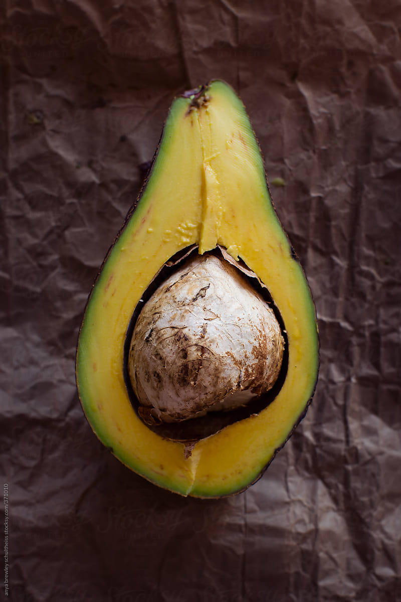 A cut avocado pear showing the seed and yellow flesh