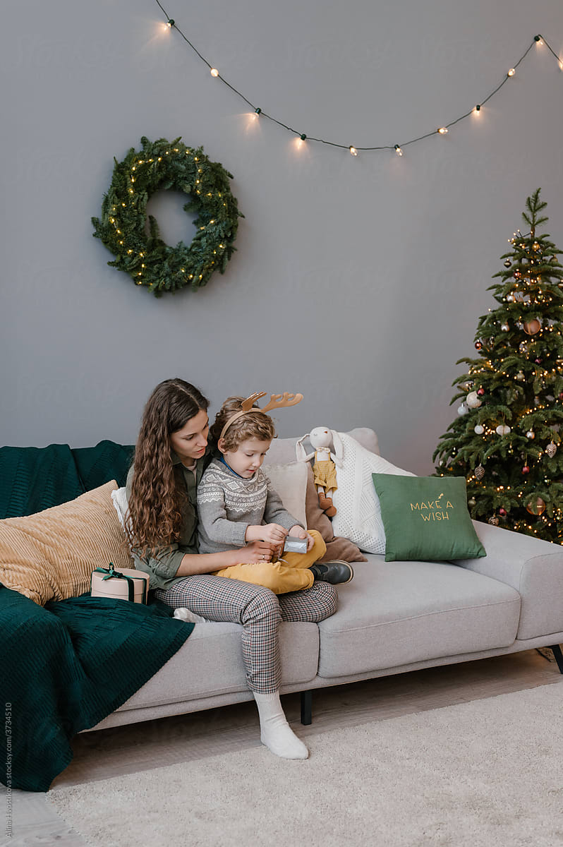 Happy woman and boy opening Christmas present on couch