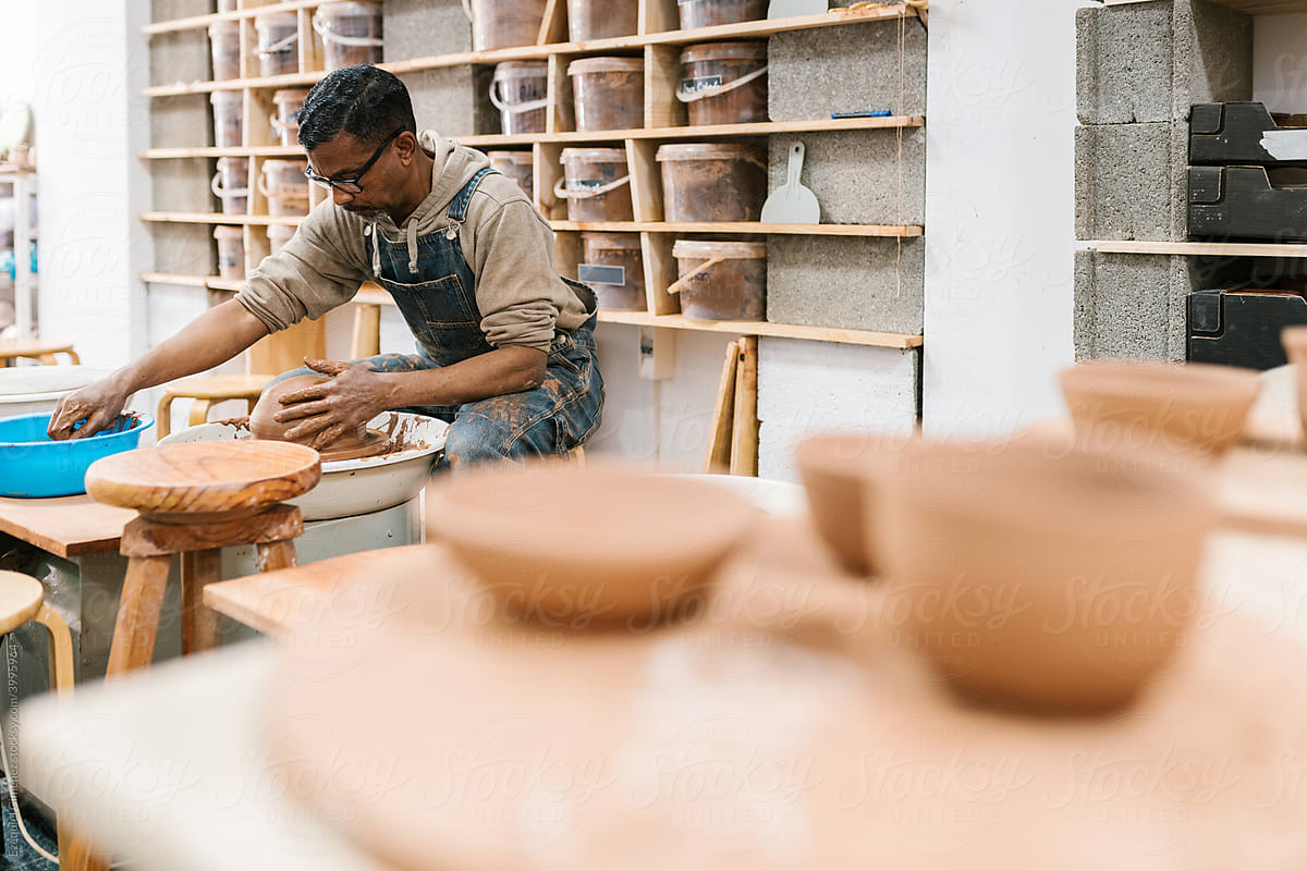 Focused ethnic craftsman working in pottery workshop