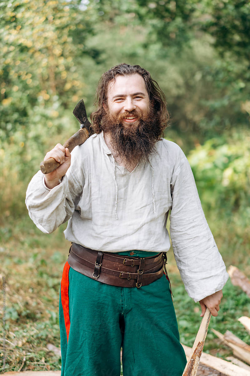 A bearded man in vintage clothing with an ax