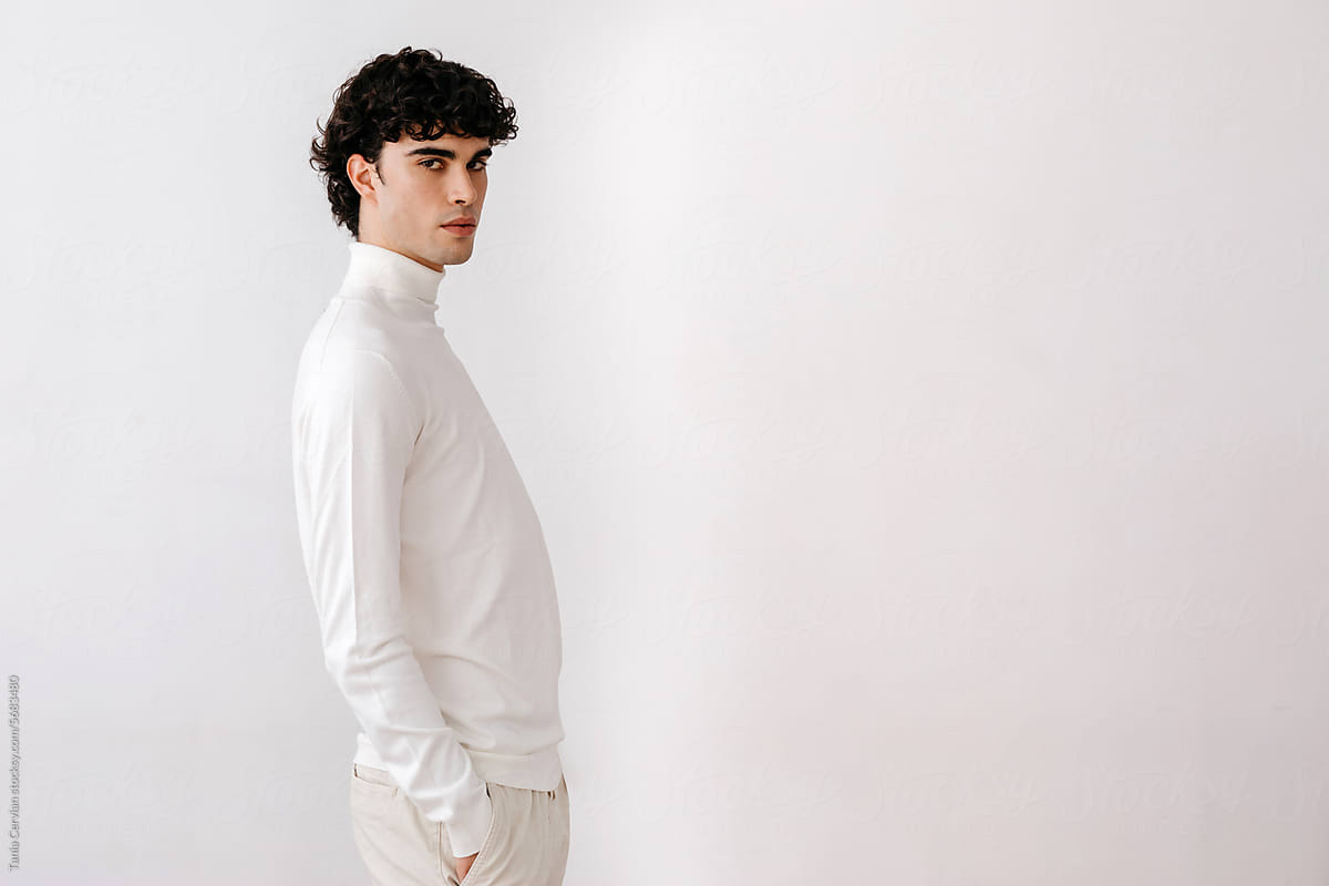 Stylish young man in white shirt standing against white background