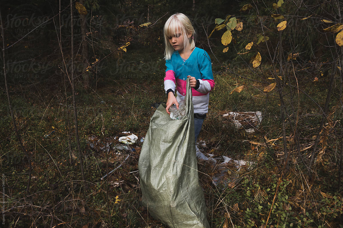 Little child collecting litter in the forest
