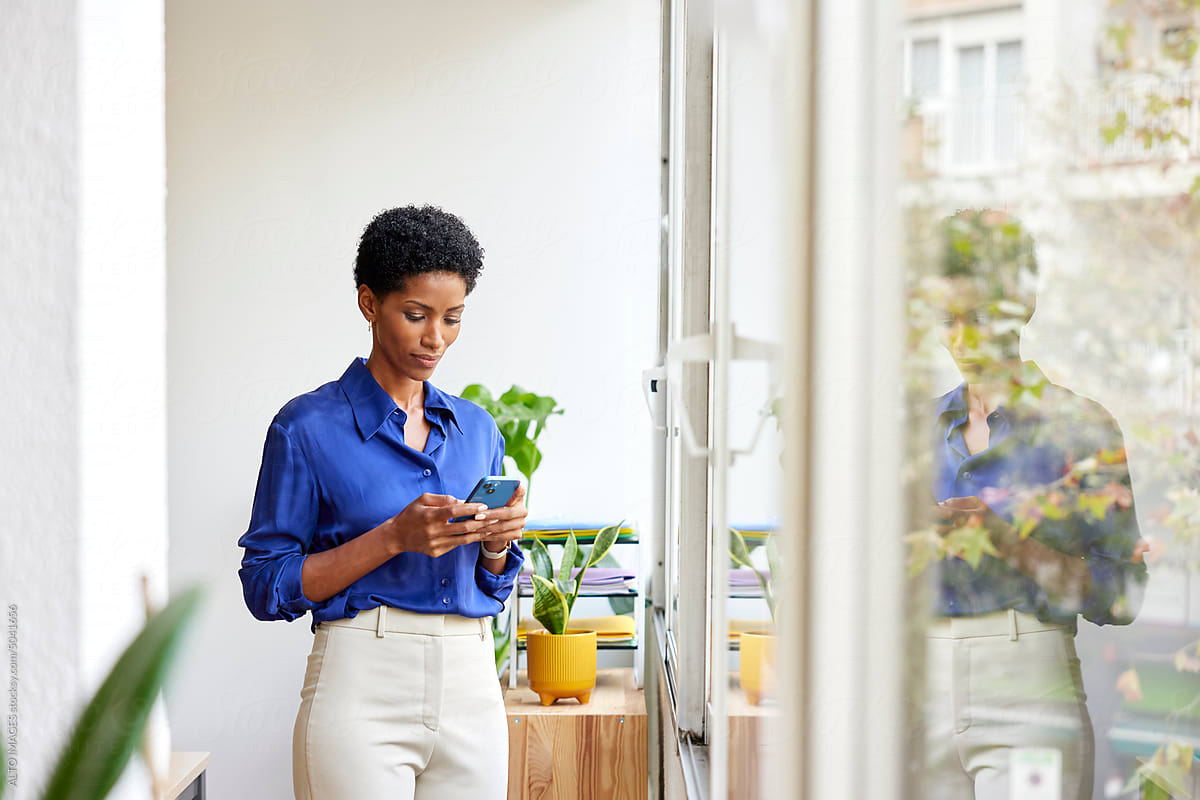 Black formal businesswoman checking smartphone