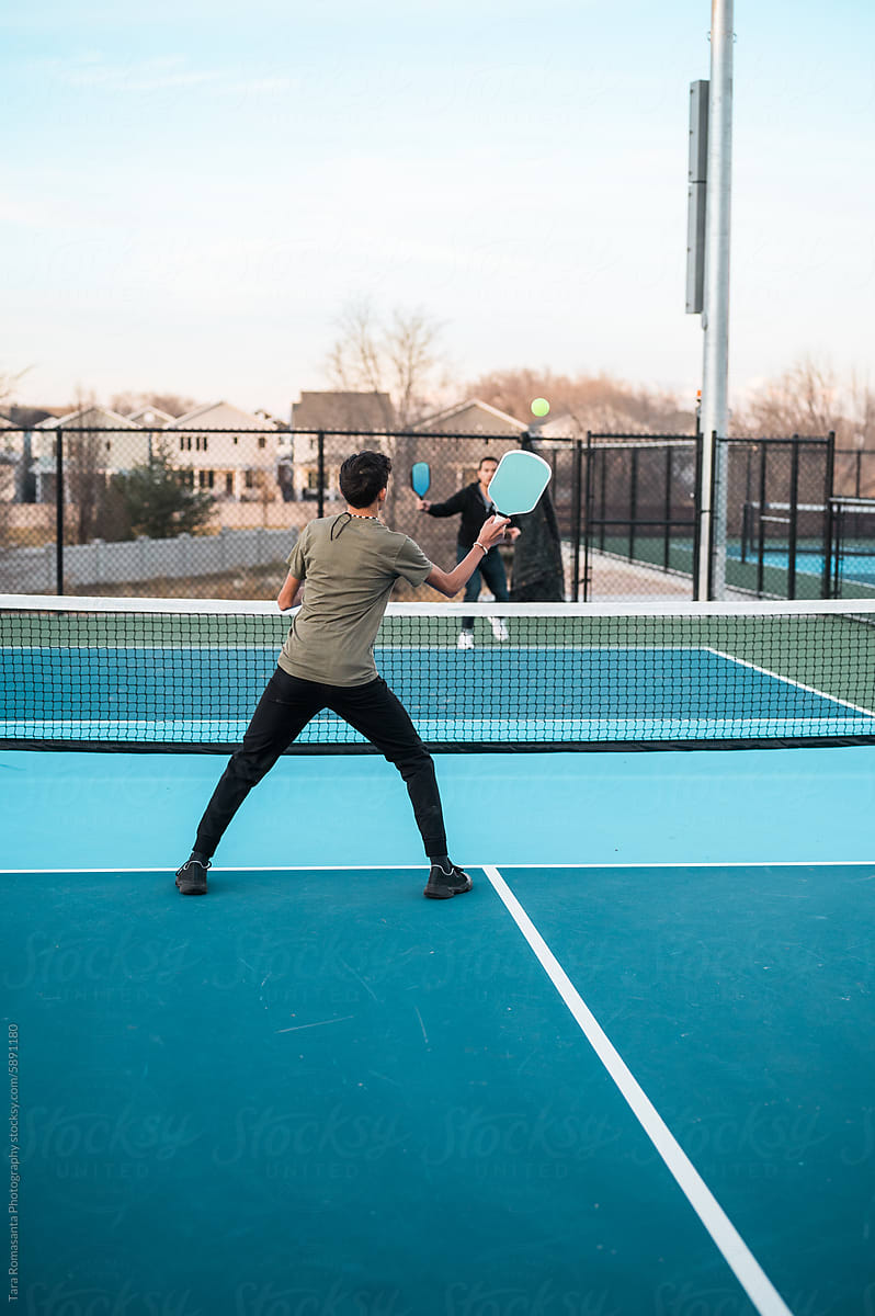 Teen playing pickle ball with father.