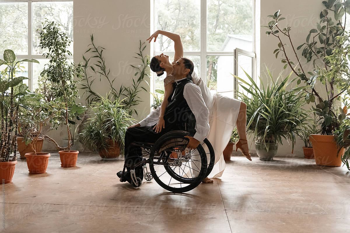 Graceful lady leaning on dance partner on wheelchair