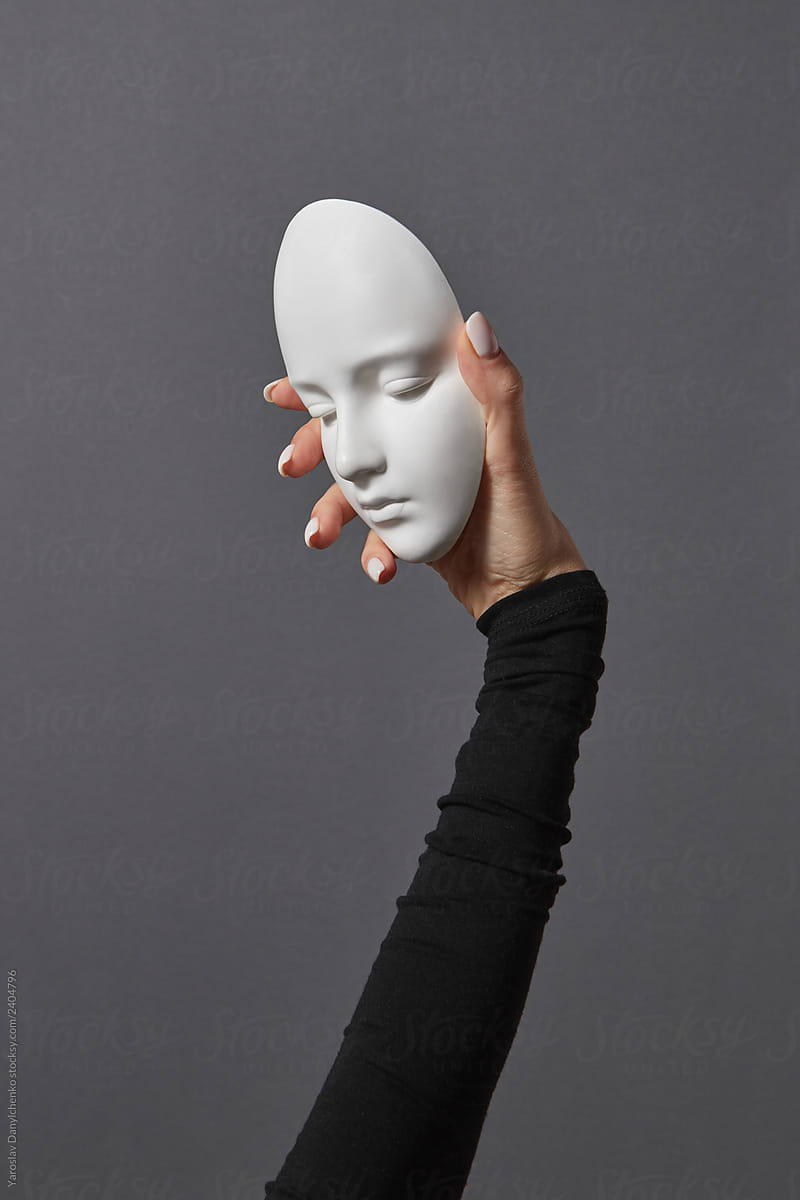 Woman's hand holding white plaster mask