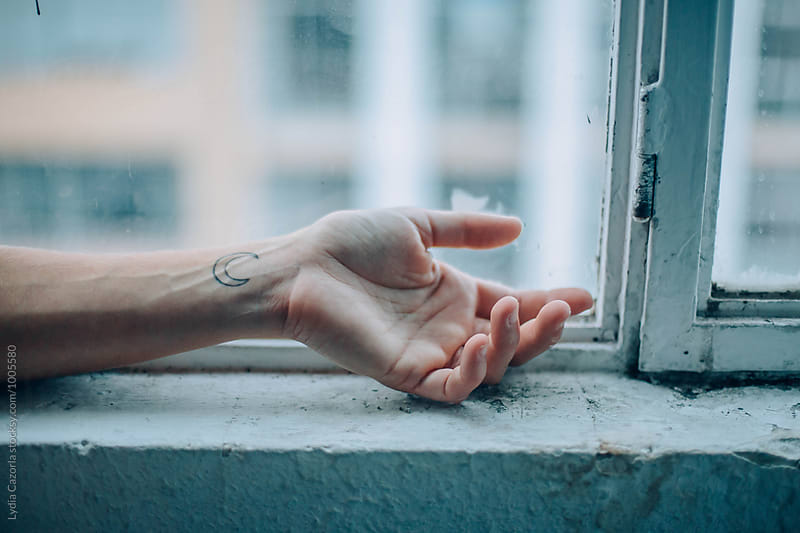 Hand with a  moon tattoo at the window