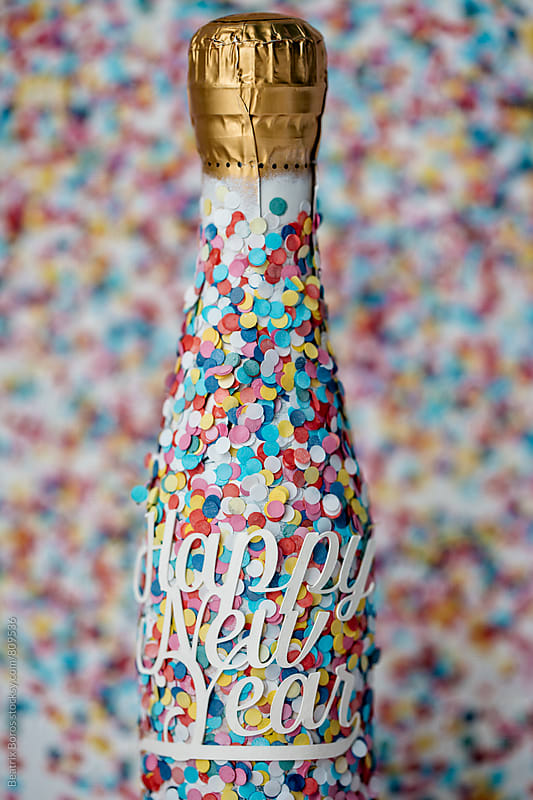 Happy new year text on a champagne bottle covered with confetti all over