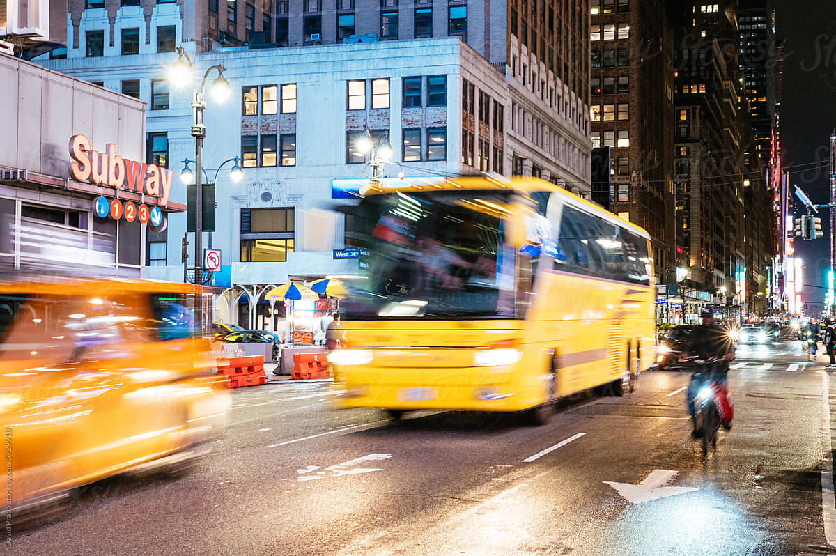 Nighttime Manhattan traffic near Subway sign.