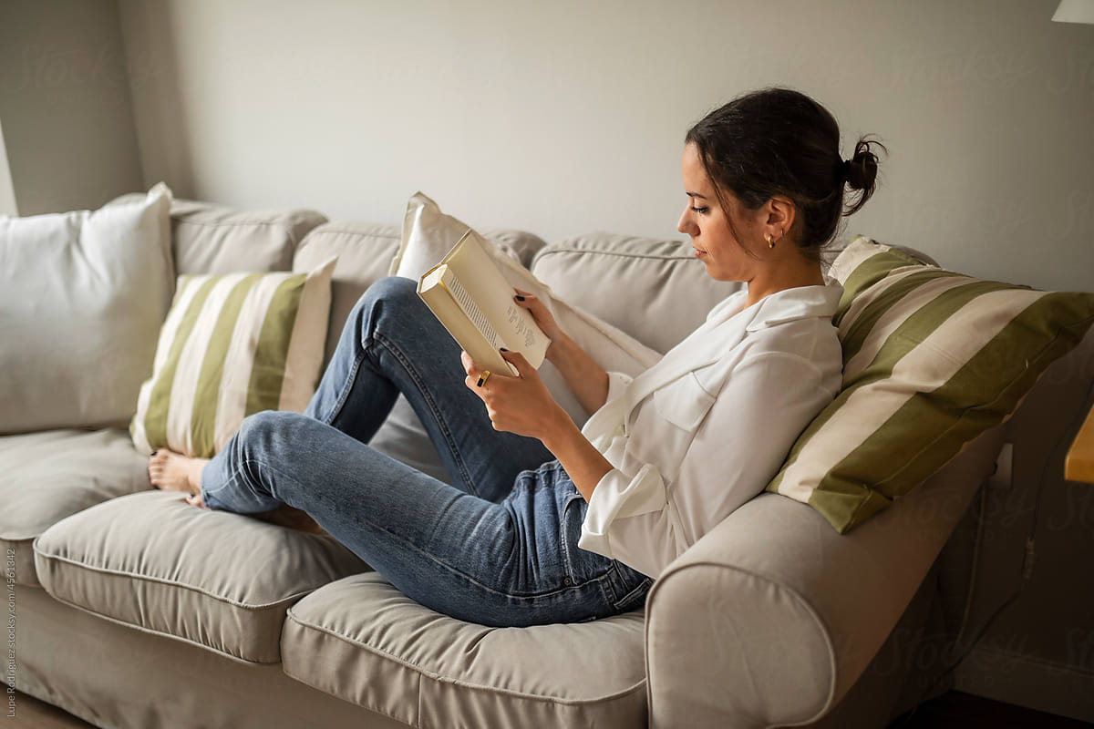 Caucasian young woman reading a book at home